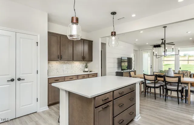 a kitchen with stainless steel appliances a refrigerator a stove a sink dishwasher a dining table and chairs with wooden floor