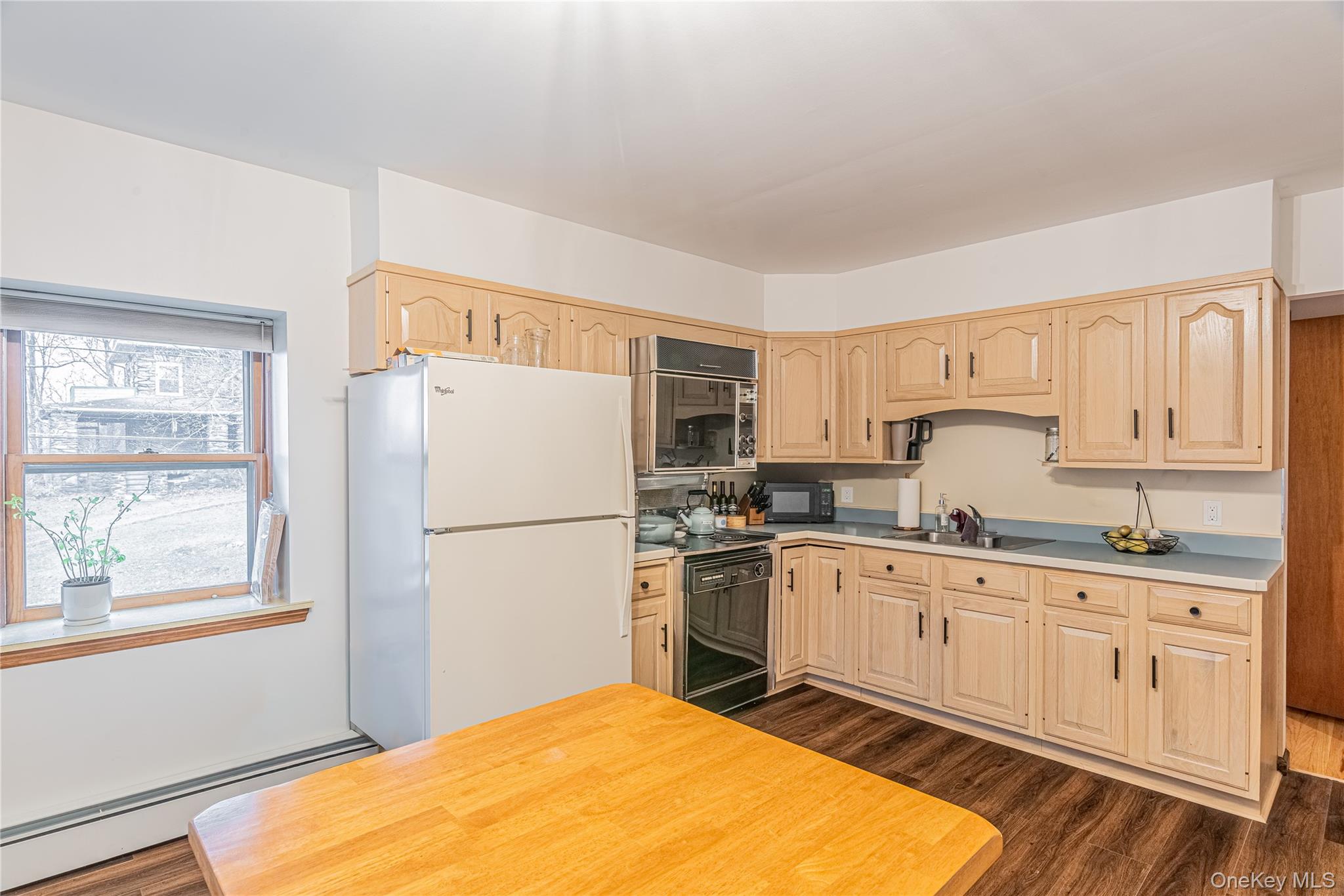 23 Musselman Drive Poughkeepsie, NY 12601 - Photo 17 of 34 Kitchen featuring black appliances, a baseboard heating unit, light brown cabinetry, light countertops, and dark wood finished floors