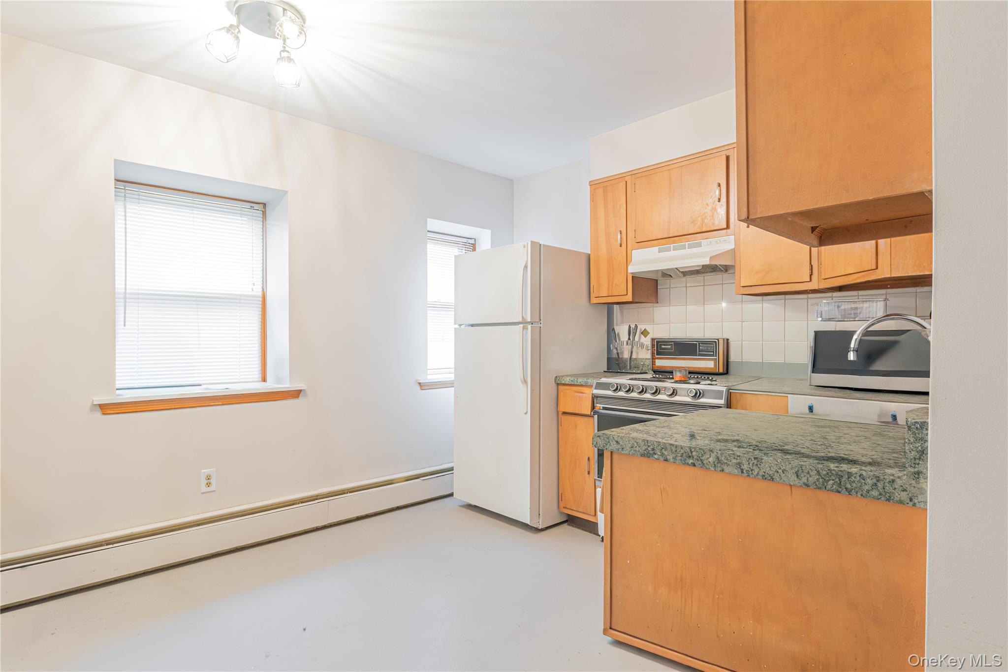 23 Musselman Drive Poughkeepsie, NY 12601 - Photo 7 of 34 Kitchen with a baseboard radiator, decorative backsplash, freestanding refrigerator