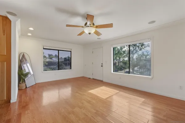 a view of empty room with wooden floor and fan