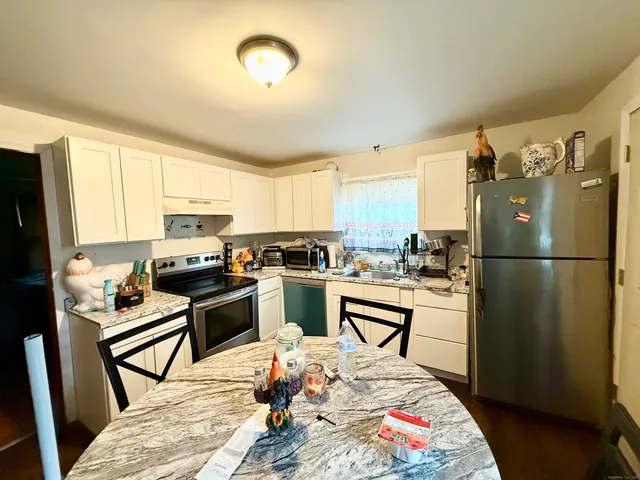 a kitchen with stainless steel appliances kitchen island granite countertop a stove a sink dishwasher a dining table and chairs with wooden floor