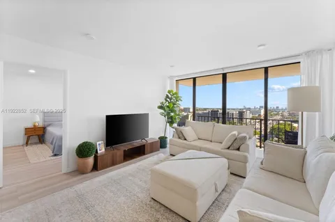 a living room with furniture a flat screen tv and floor to ceiling window
