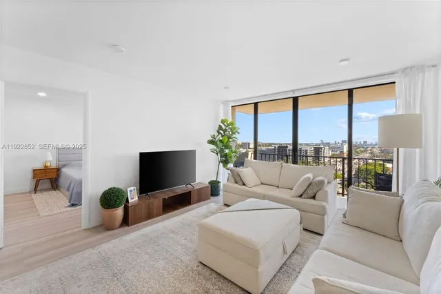 a living room with furniture a flat screen tv and floor to ceiling window