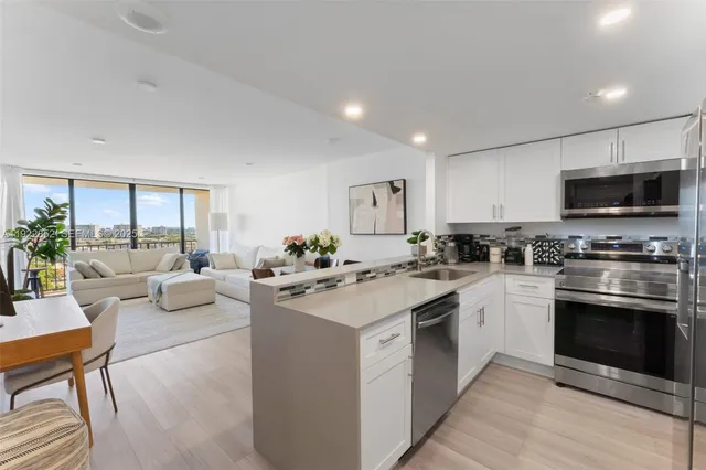 a kitchen with stainless steel appliances granite countertop a stove top oven a sink dishwasher a dining table and chairs with wooden floor