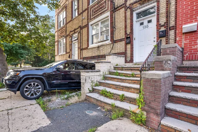 a front view of a house with a garden and parking space