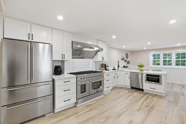 a kitchen with white cabinets stainless steel appliances and window