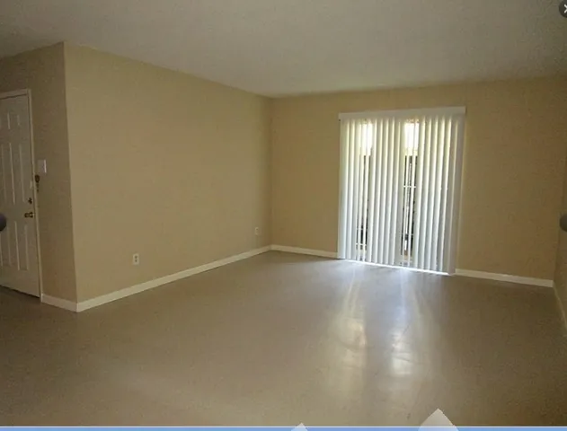 an empty room with wooden floor and windows with curtains
