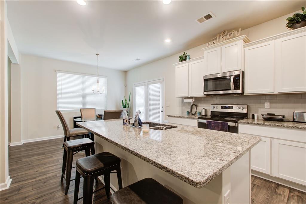 11898 Lovejoy Crossing Boulevard Hampton, GA 30228 - Photo 9 of 30 a kitchen with granite countertop kitchen island white cabinets appliances and wooden floor