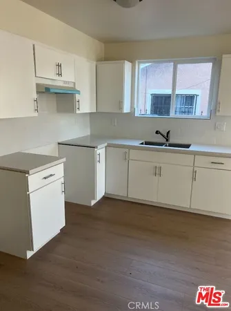 a kitchen with stainless steel appliances granite countertop a sink cabinets and a wooden floor