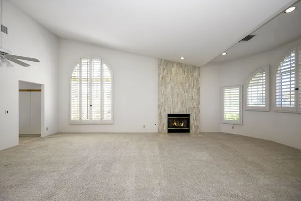 an empty room with windows and fireplace