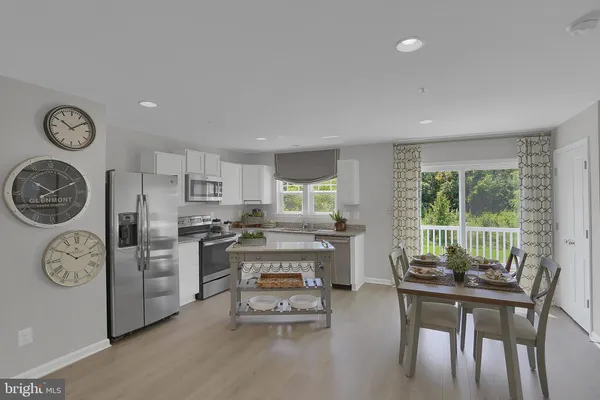 a room with stainless steel appliances a dining table and chairs