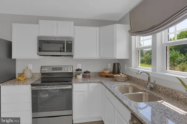 a kitchen with granite countertop a sink a stove a microwave and wooden cabinets