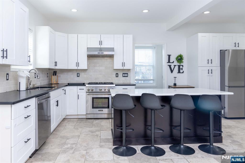 126 Ridge Avenue Bloomfield, NJ 07003 - Photo 12 of 45 a kitchen with stainless steel appliances kitchen island granite countertop a table chairs sink and cabinets