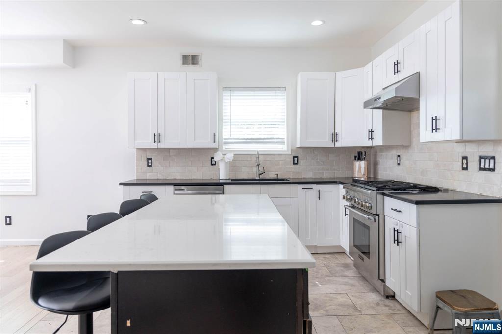126 Ridge Avenue Bloomfield, NJ 07003 - Photo 13 of 45 a kitchen with stainless steel appliances a sink a stove a refrigerator a center island and a cabinets