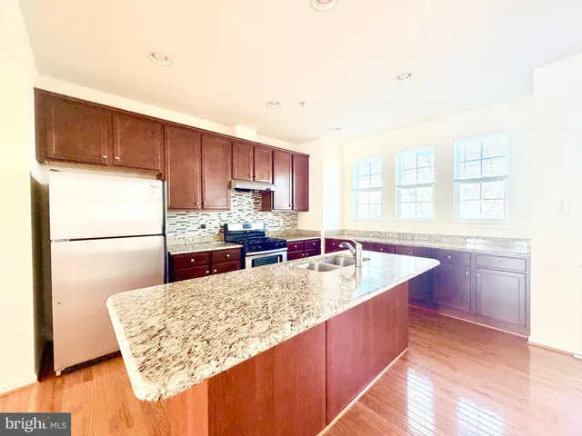 a kitchen with stainless steel appliances granite countertop a sink counter space and a refrigerator