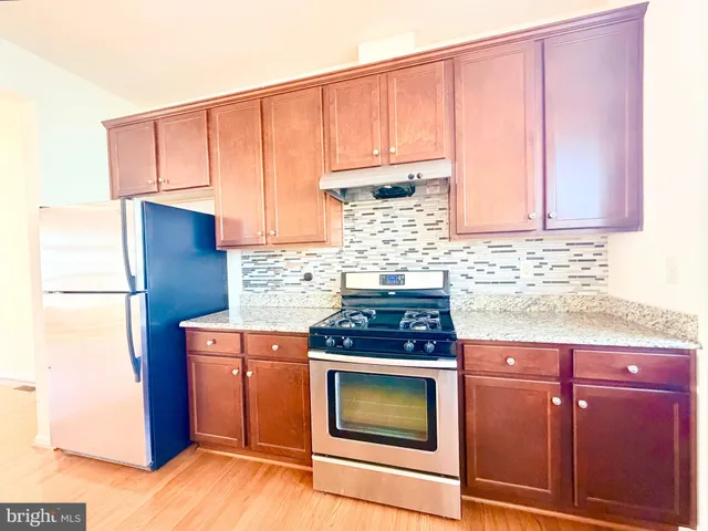 a kitchen with stainless steel appliances granite countertop wooden cabinets a stove a sink and dishwasher