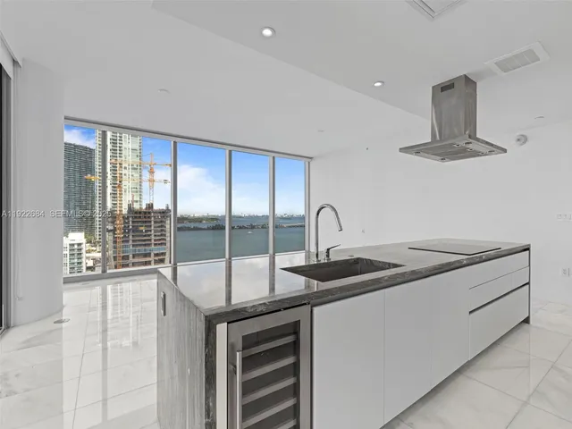 a kitchen with kitchen island a sink appliances cabinets and a large window