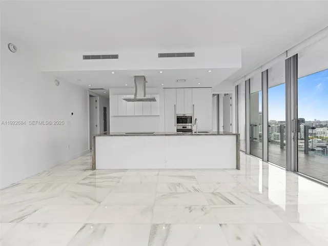 a large white kitchen with kitchen island a stove a refrigerator and cabinets