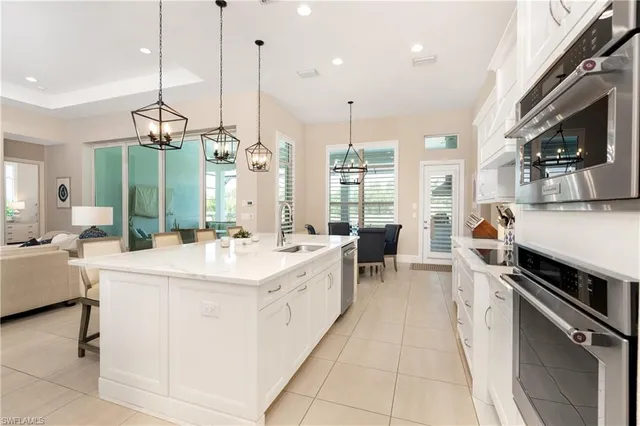 a large kitchen with stainless steel appliances kitchen island a large counter tops a stove a sink and dishwasher a refrigerator with wooden floor