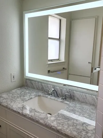 a bathroom with a granite countertop sink and a mirror