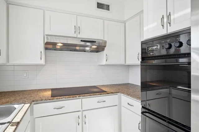 a kitchen with granite countertop white cabinets and stainless steel appliances