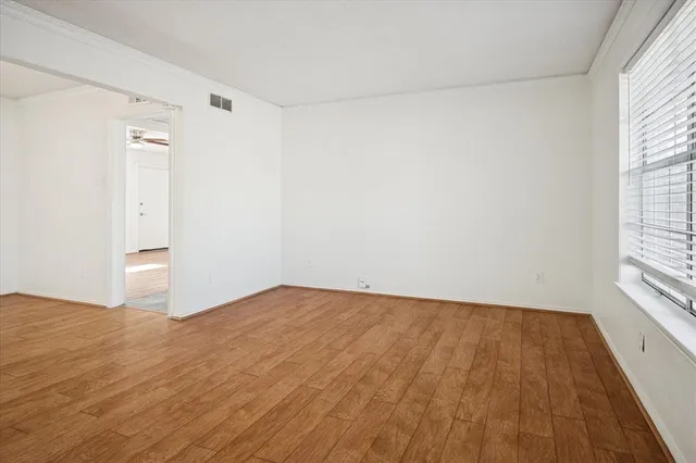 a view of an empty room with a window and wooden floor