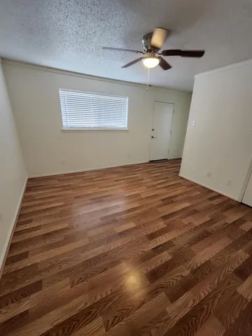 a view of a room with wooden floor and a ceiling fan