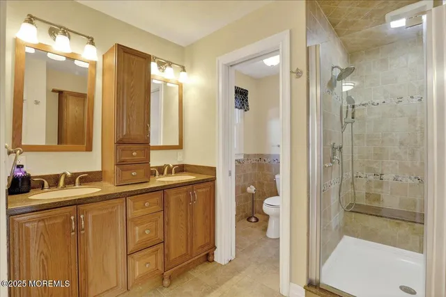 a bathroom with a double vanity sink toilet mirror and windows
