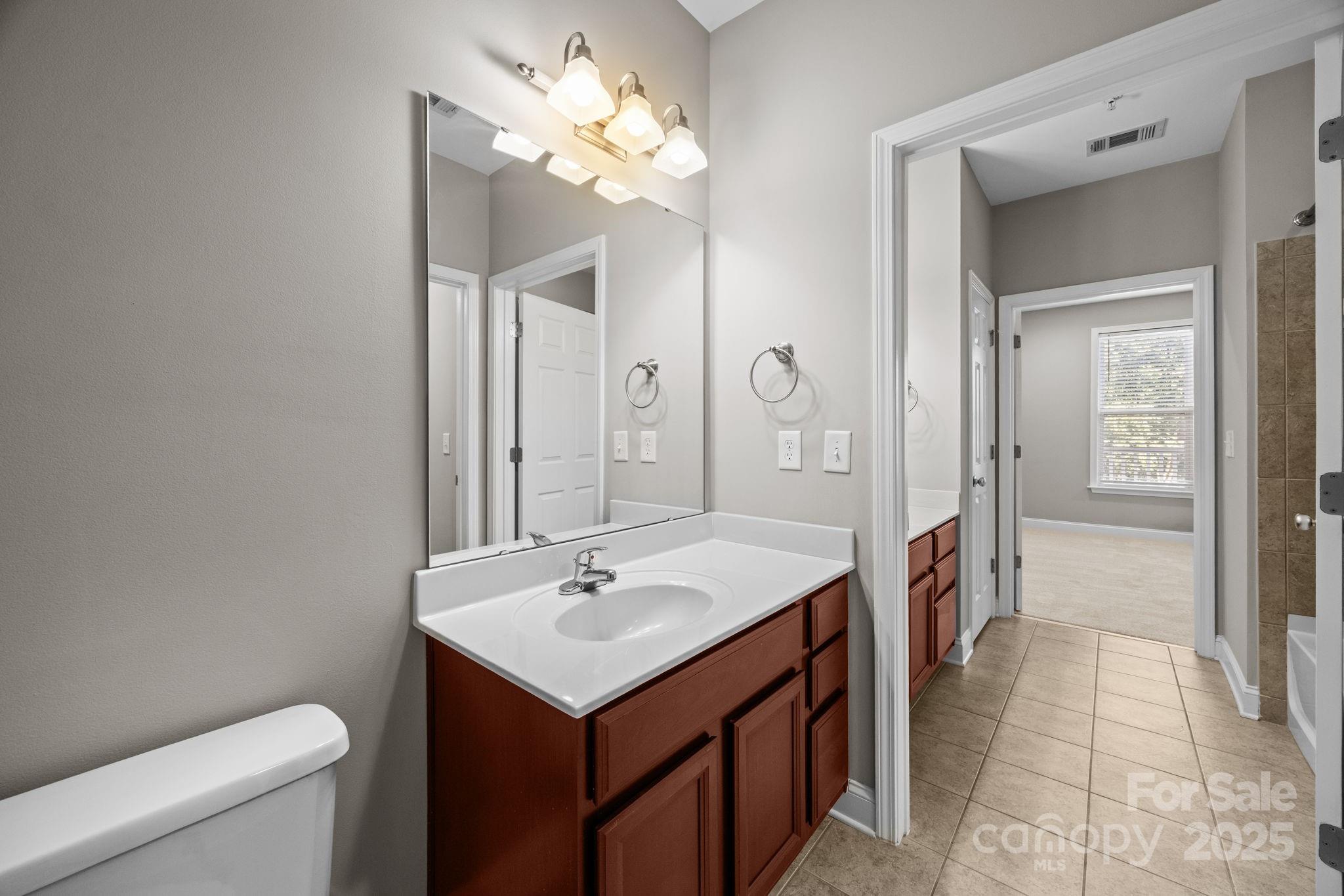 1000 East Woodlawn Road, Unit 413 Charlotte, NC 28209 - Photo 19 of 32 a bathroom with a sink a toilet and a mirror