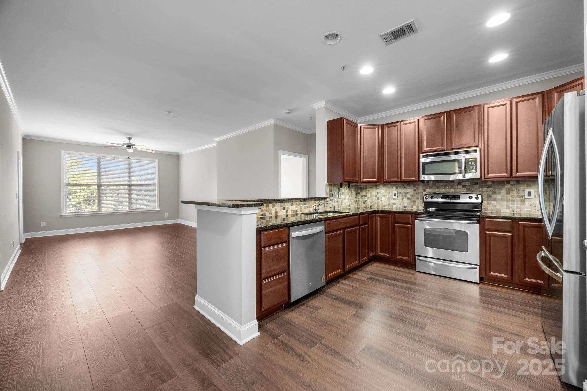 1000 East Woodlawn Road, Unit 413 Charlotte, NC 28209 - Photo 7 of 32 a kitchen with stainless steel appliances granite countertop a stove a sink dishwasher a refrigerator and a microwave oven with wooden floor