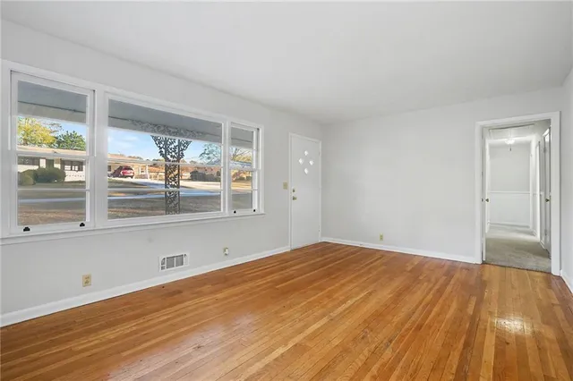 a view of empty room with wooden floor and fan