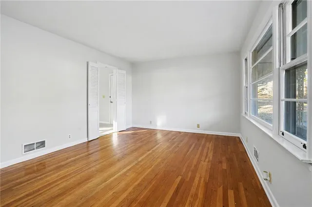 a view of an empty room with wooden floor and a window