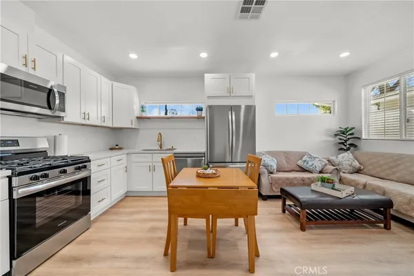 a living room with stainless steel appliances kitchen island granite countertop a stove a sink a refrigerator and blue cabinets