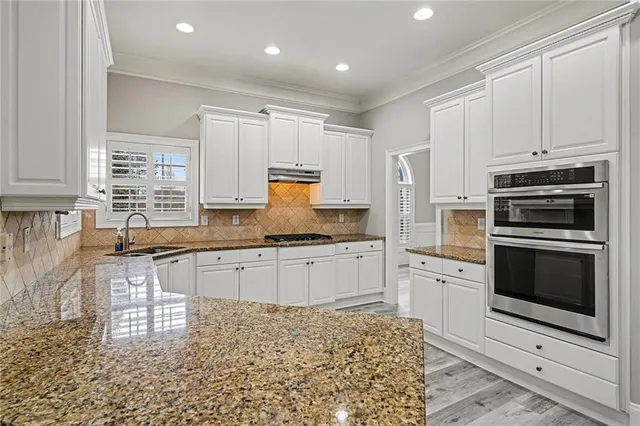 a kitchen with kitchen island granite countertop a stove top oven a sink a counter space and cabinets