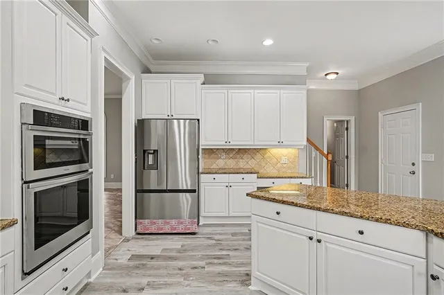 a kitchen with granite countertop stainless steel appliances a refrigerator cabinets and microwave