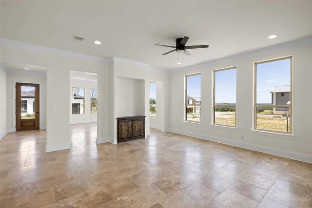 a view of an empty room with a kitchen and window