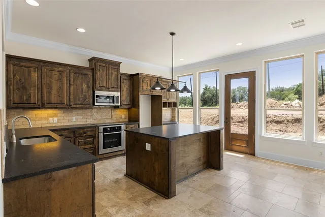 a kitchen with stainless steel appliances granite countertop a stove top oven a refrigerator a sink and dishwasher