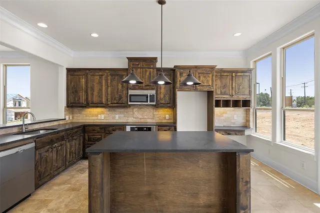 a kitchen with stainless steel appliances granite countertop a sink a stove and a wooden floor
