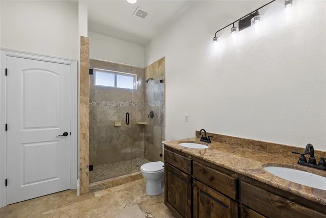 a bathroom with a granite countertop sink a mirror a toilet and shower
