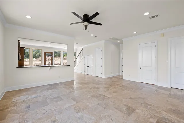 an empty room with ceiling fan and windows