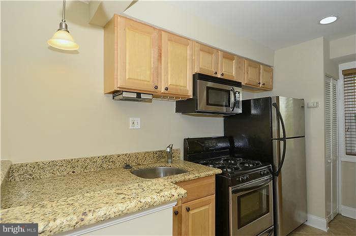 8708 Bradford Road, Unit 301 Silver Spring, MD 20901 - Photo 2 of 13 a kitchen with granite countertop a stove and a refrigerator