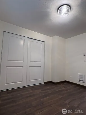 a view of an empty room with wooden floor and a cabinet