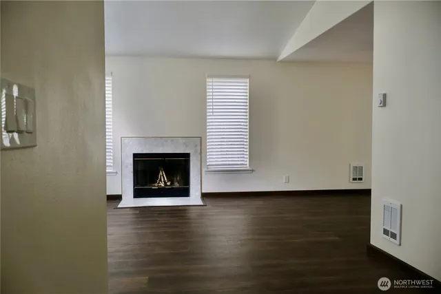 a view of an empty room with wooden floor fireplace and a window