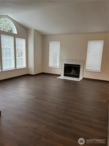 an empty room with windows fireplace and sink