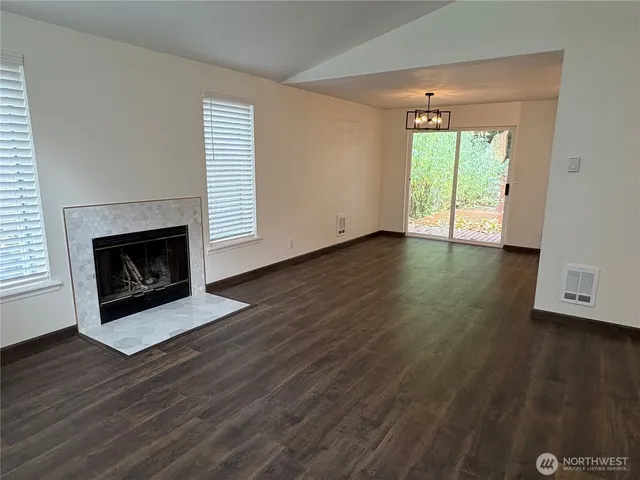 an empty room with wooden floor fireplace and windows