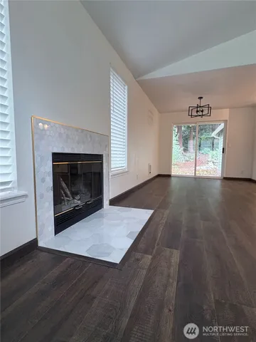 an empty room with wooden floor fireplace and windows