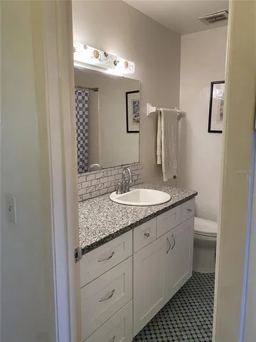 a bathroom with a granite countertop sink and a mirror