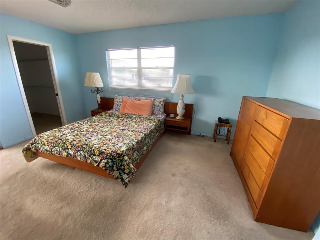 4101 Oakridge V, Unit 4101 Deerfield Beach, FL 33442 - Photo 11 of 42 a bed sitting in a bedroom next to a window