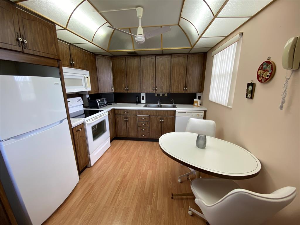 4101 Oakridge V, Unit 4101 Deerfield Beach, FL 33442 - Photo 5 of 42 a kitchen with wooden cabinets a sink a stove a refrigerator and island