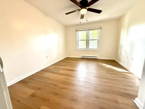 an empty room with wooden floor fan and windows